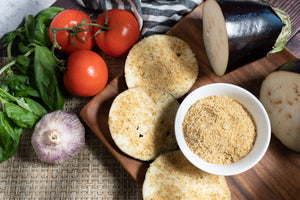 Gluten-free bread crumbs shown with fresh vegetables and bread rounds for cooking and coating recipes